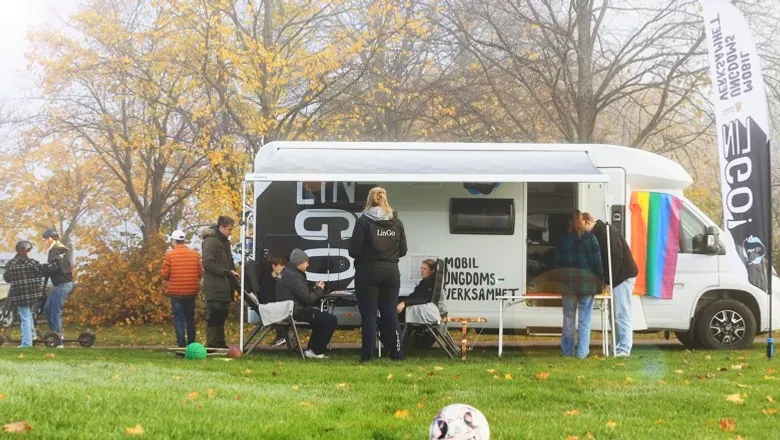 En grupp människor som står runt en husbil.