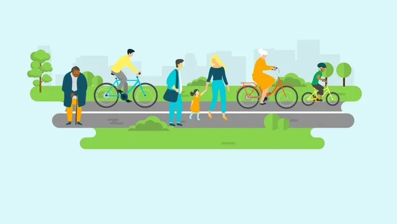 Vy över gång- och cykelbana. Människor som promenerar och cyklar. I Bakgrunden grönområde med träd och en stadssiluett.