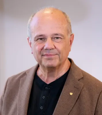 En man klädd i brun kavaj och svart tröja.