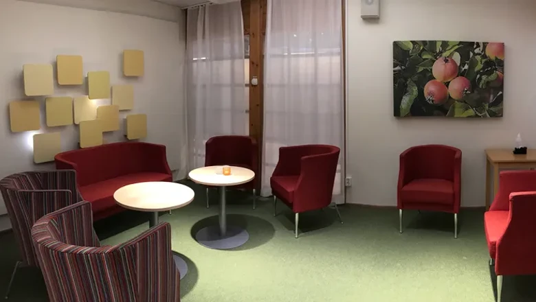 Ett rum med stolar, ett bord och en tavla på väggen