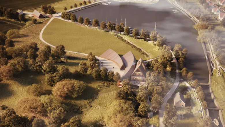 En flygbild av en modern byggnad omgiven av träd och vatten.