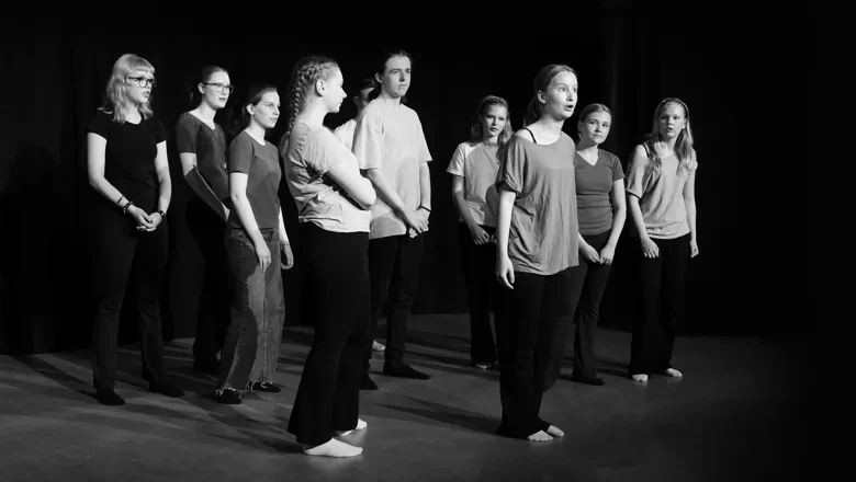 Svartvitt fotografi av en grupp människor som står på en teaterscen
