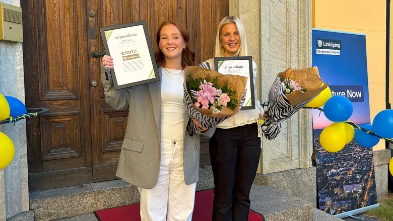 Mira och Alma står på en röd matta och håller i blommor.